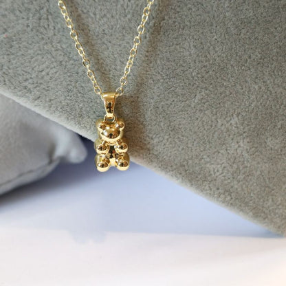 Gold necklace with a bear-shaped pendant on a soft gray background